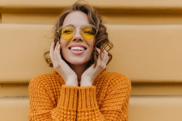 Joyful lady with pale skin enjoying photoshoot outdoor and smiling