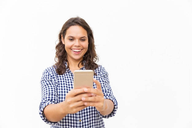Радостная латинская женщина со смартфоном смотрит смешной контент