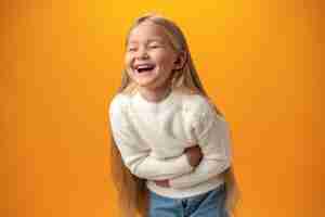 Free photo joyful laughter of little blonde girl against yellow background in studio