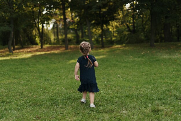 Joyful little girl running on green grass