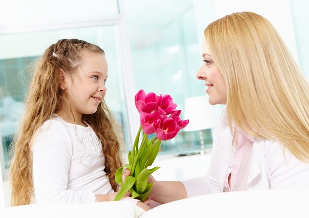 Радостный маленькая девочка с цветами для своей матери