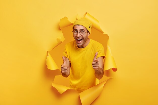 Joyful man posing through torn paper