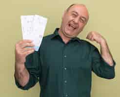 Free photo joyful middle-aged man wearing green t-shirt holding tickets showing strong gesture isolated on olive green wall