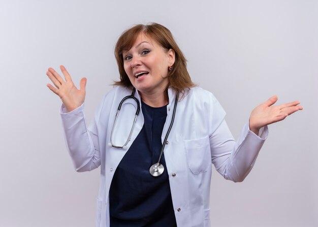 医療ローブと分離の白い壁に空の手を示す聴診器を着てうれしそうな中年女性医師