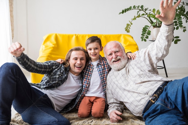 Free photo joyful multi-generational family sitting on carpet together