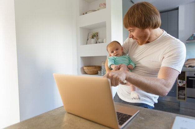 Joyful new dad and his baby daughter watching content