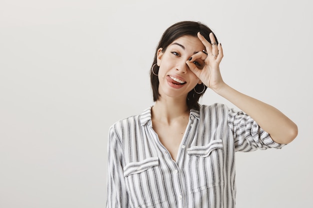 Joyful optimistic girl showing okay gesture and smiling pleased