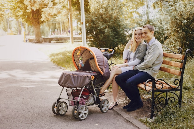 Joyful parents with stroller on a park bench