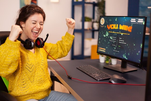 Joyful player celebrates victory winning space shooter online video game on powerful personal computer