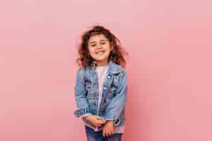 Foto gratuita bambino allegro del preteen con capelli ricci che ride della macchina fotografica. studio shot di spensierata bambina isolata su sfondo rosa.