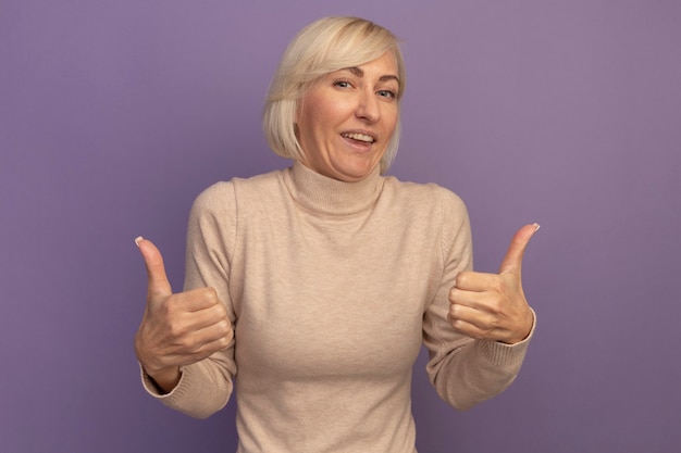 Free photo joyful pretty blonde slavic woman thumbs up of two hands on purple