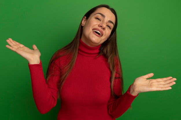 Joyful pretty caucasian woman holds hands open on green