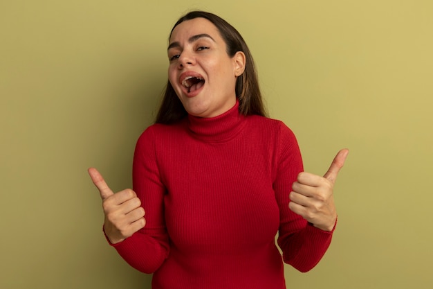 Joyful pretty caucasian woman thumbs up of two hands on olive green