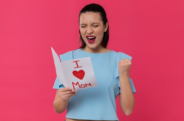 Joyful pretty young woman reading letter from her child and keeping fist