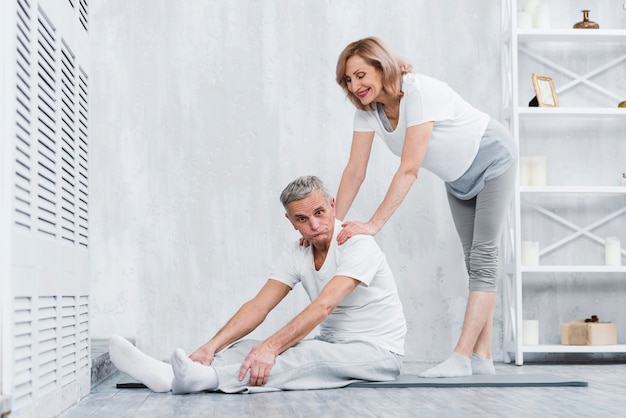 Joyful senior couple making fun while exercising at home