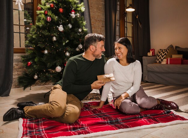 Joyful senior couple smiling and gifting gifts each other