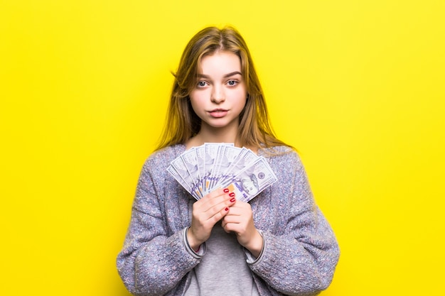 Joyful teenage girl with dollars in her hands isolated