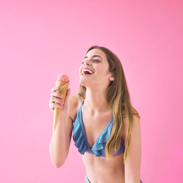 Радостная женщина в бикини с мороженым