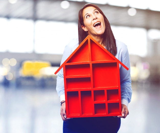 Joyful woman holding a wooden house