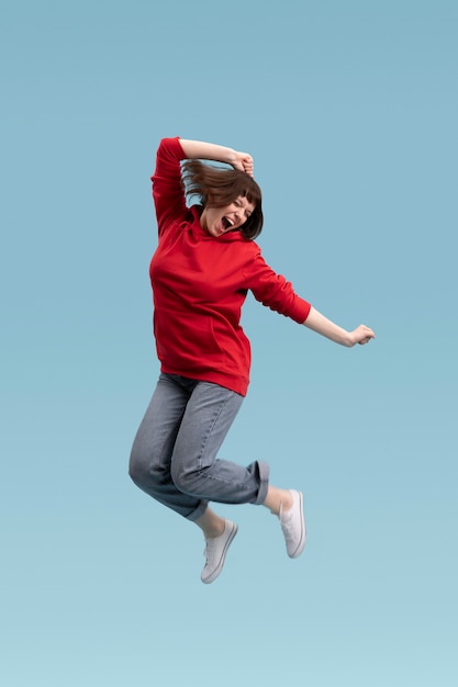 Joyful woman jumping isolated on blue