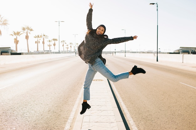 Foto gratuita donna gioiosa saltando in mezzo alla strada