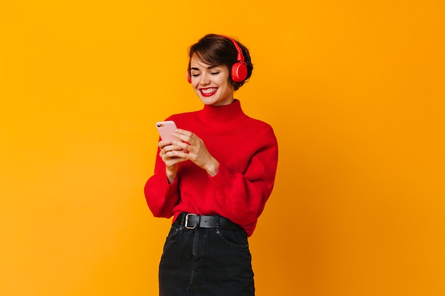 Joyful woman listening music and looking at smartphone