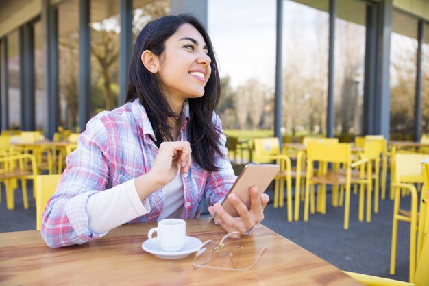 Радостная женщина с помощью смартфона и пить кофе в кафе