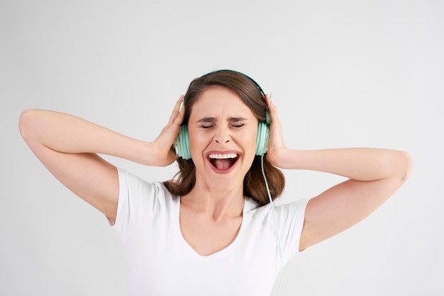Радостная женщина с наушниками, слушающая музыку