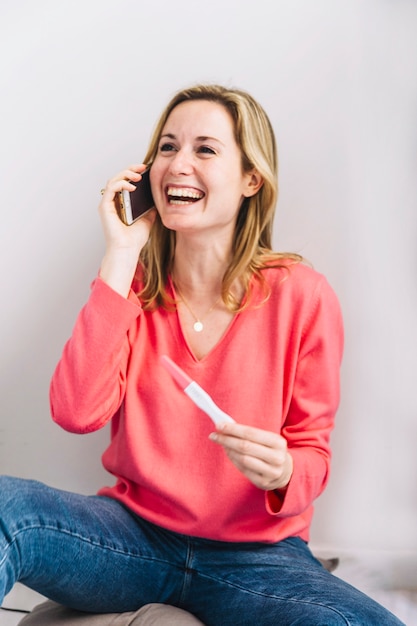 전화 통화하는 임신 테스트와 즐거운 여자