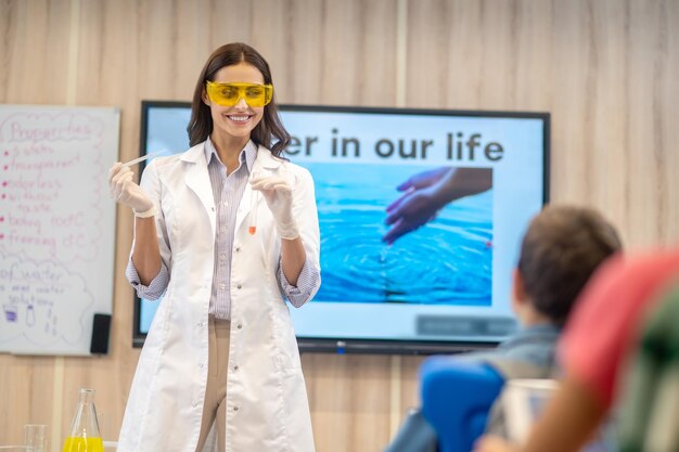 Joyful woman with test tube looking at children