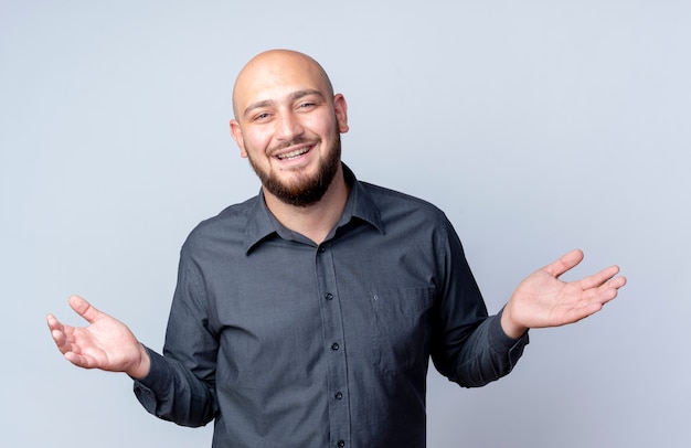 Joyful young bald call center man showing empty hands isolated on white