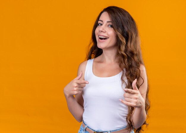 Joyful young beautiful girl showing thumb up and pointing at it on isolated orange space with copy space
