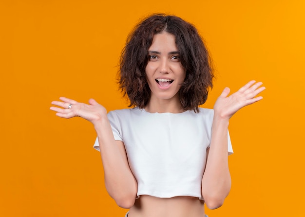 Joyful young beautiful woman with open arms on isolated orange wall