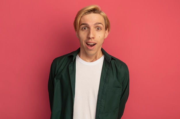 Joyful young blonde guy wearing green t-shirt holding hands on waist