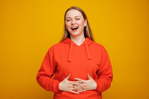 Joyful young blonde woman keeping hands on belly laughing 