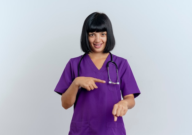 Foto gratuita gioiosa giovane dottoressa bruna in uniforme con stetoscopio