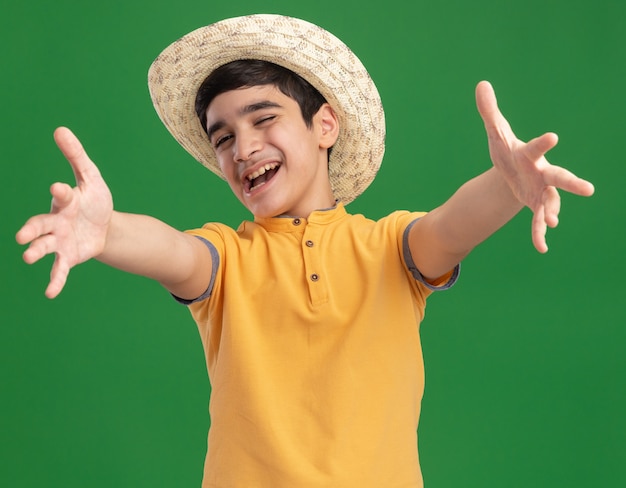 Joyful young caucasian boy wearing beach hat spreading hands winking