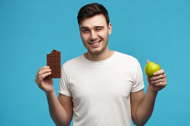 Joyful young Caucasian brunette guy in white t-shirt made wrong choice