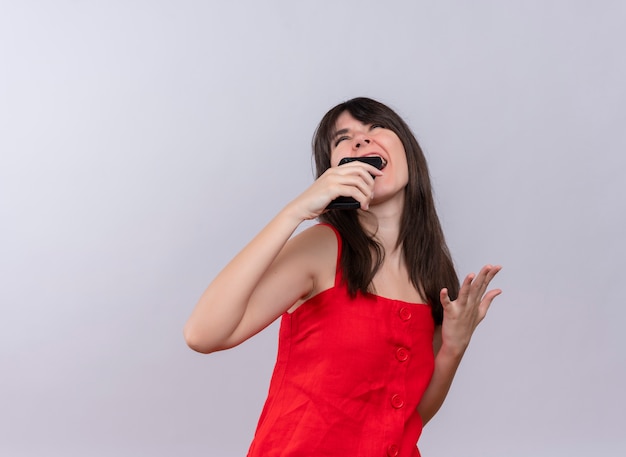 Gioiosa giovane ragazza caucasica tenendo il telefono con la mano aperta e alzando lo sguardo su sfondo bianco isolato con copia spazio