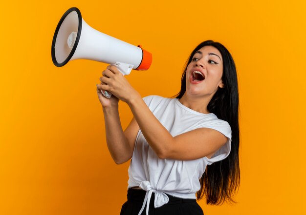 Joyful young caucasian girl holds loud speaker looking at side 