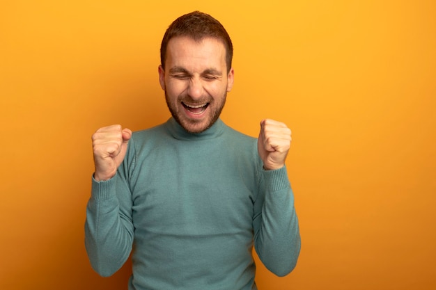 Joyful young caucasian man doing yes gesture with closed eyes isolated on orange wall with copy space