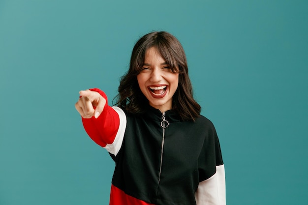 Joyful young caucasian woman looking and pointing at side laughing isolated on blue background