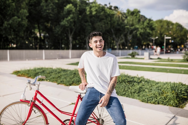 Радостный молодой велосипедист, сидящий на заднем сиденье своего велосипеда