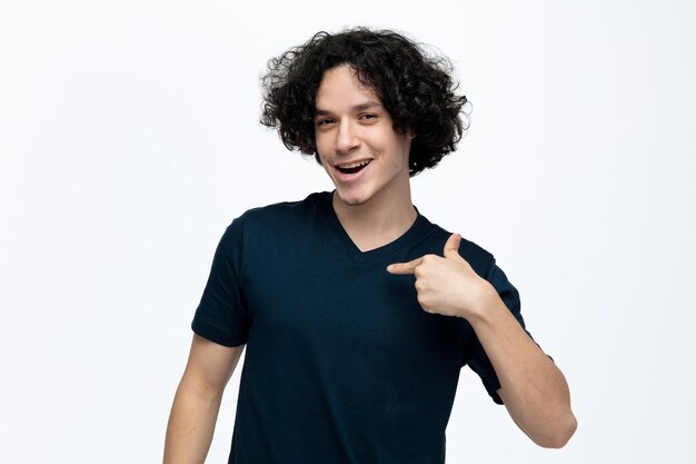 Joyful young handsome man looking at camera doing choose me gesture isolated on white background