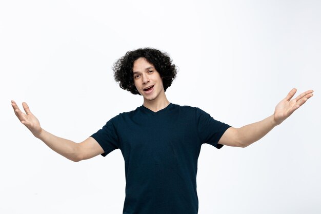 Joyful young handsome man looking at camera doing welcome gesture isolated on white background