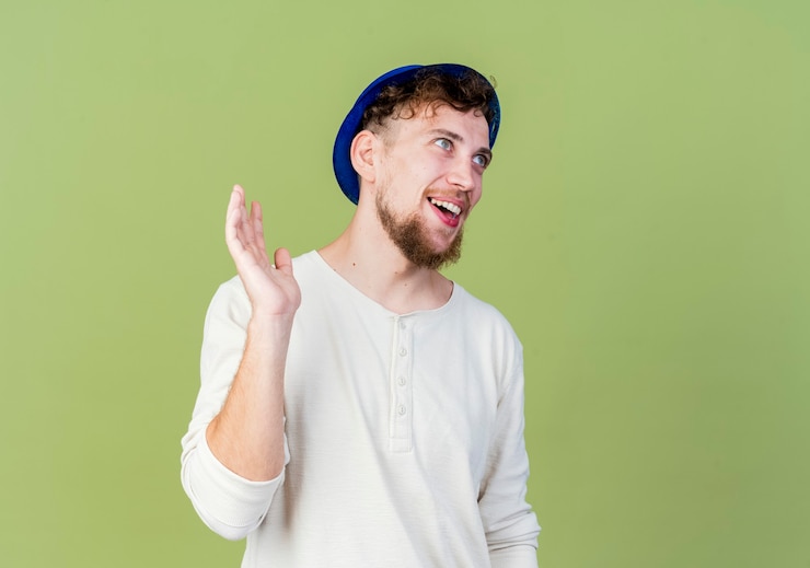 Free Photo joyful young handsome slavic party guy wearing party hat looking straight waving at someone isolated on olive green background with copy space