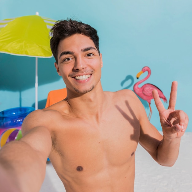 Foto gratuita giovane allegro che prende selfie sulla spiaggia in studio