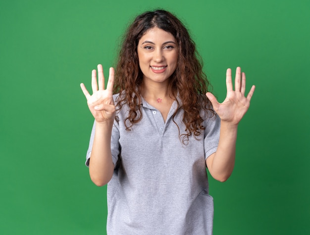 Бесплатное фото Радостная молодая симпатичная кавказская девушка показывает девять руками, изолированными на зеленой стене с копией пространства