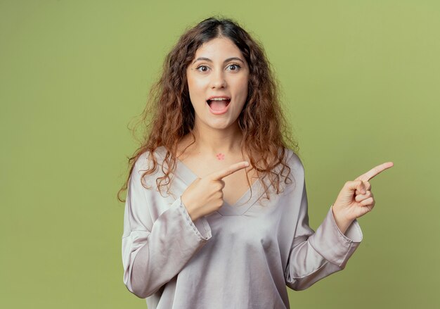 Joyful young pretty female office worker points at side  