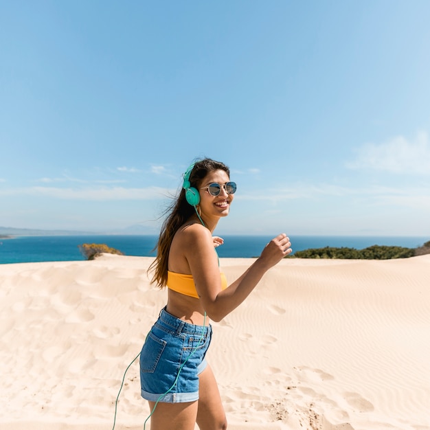 Joyful young woman in headphones on seaside